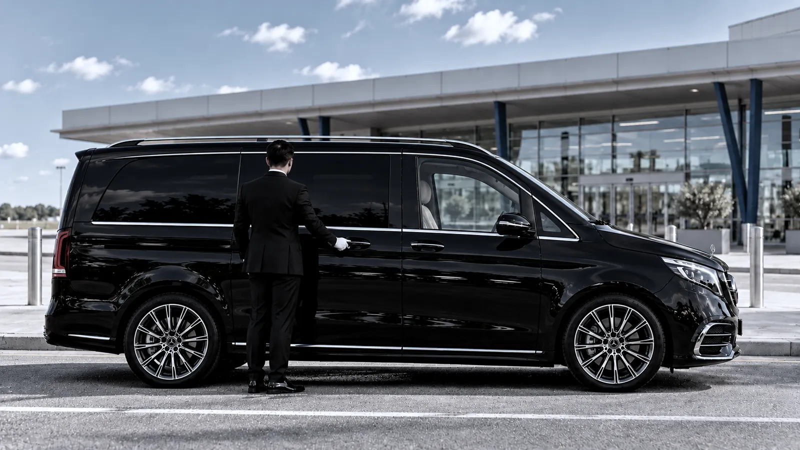 Transfert privé Aéroport de Beauvais → Beaune Chauffeur à la porte coulissante d'un Mercedes Classe V à l'aéroport de Beauvais, pour un transfert privé, destination Beaune